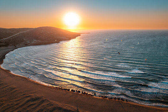 Golden Sunset Over Tranquil Seaside Waves and Distant Hills at a Serene Beach Location
