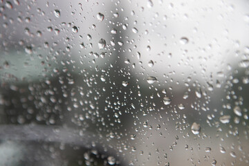 The droplets vary in size and create a bokeh effect with a blurred background, suggesting a rainy day