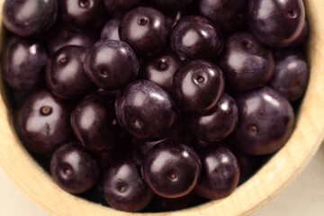 Ripe acai berries in wooden bowl, top view