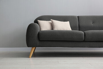 Comfortable sofa with cushions near grey wall in room