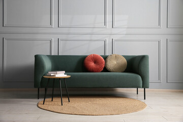 Comfortable sofa and side table near grey wall in room