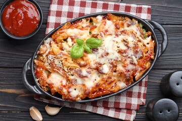 Delicious al forno pasta in baking dish on wooden table, flat lay