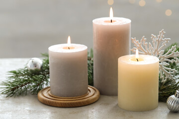 Burning candles, baubles and fir tree branches on white textured table, closeup