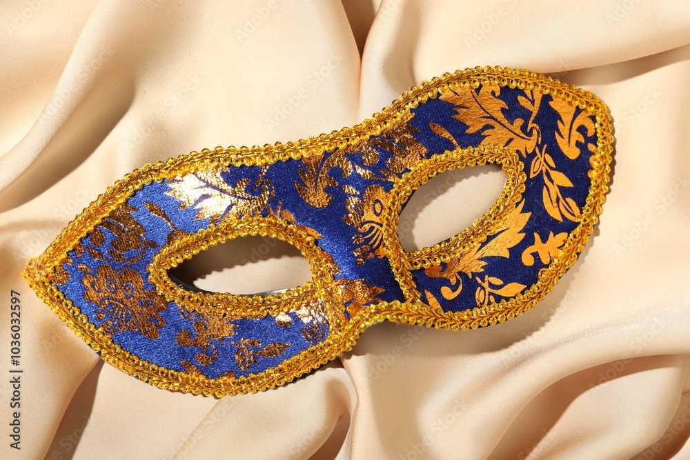 Sticker Beautiful bright carnival mask on beige fabric, top view