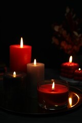Beautiful burning candles and decor on black table, closeup