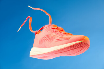 One stylish bright sneaker in air against light blue background