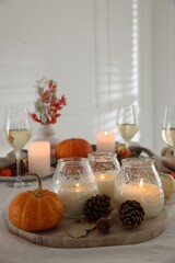 Burning candles and autumn decor on table indoors