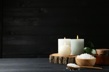 Composition with cosmetic products and candles for spa treatment on black wooden table, space for text