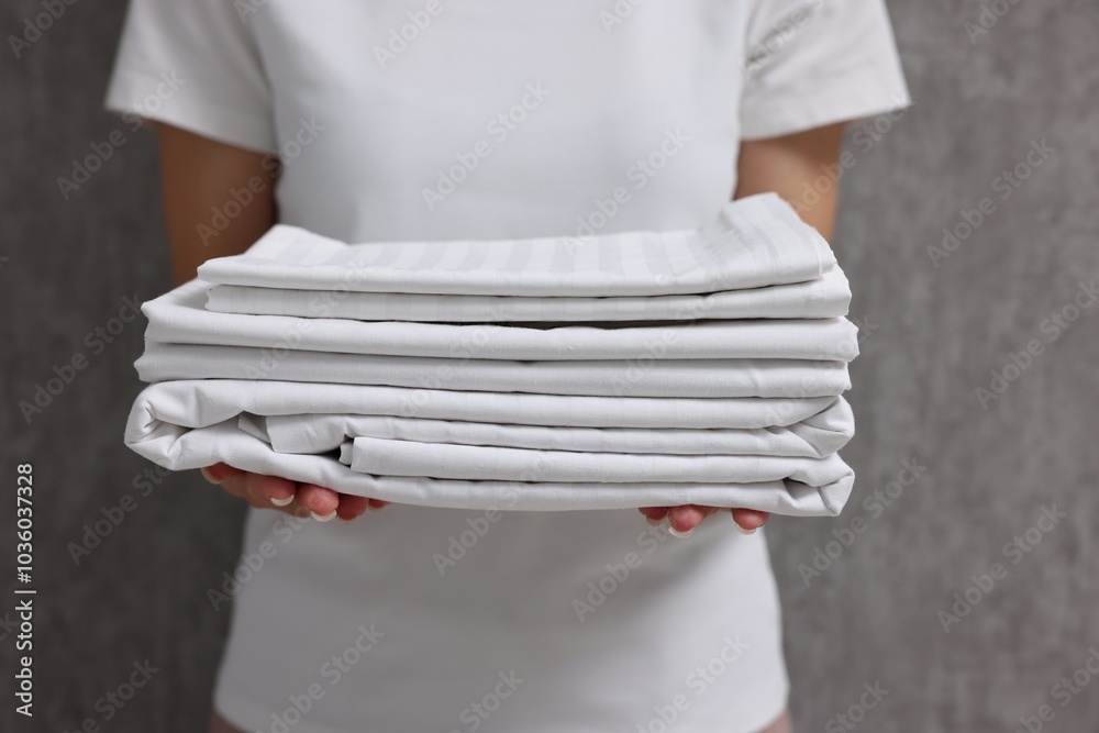 Poster Woman with clean bed linens near grey wall, closeup