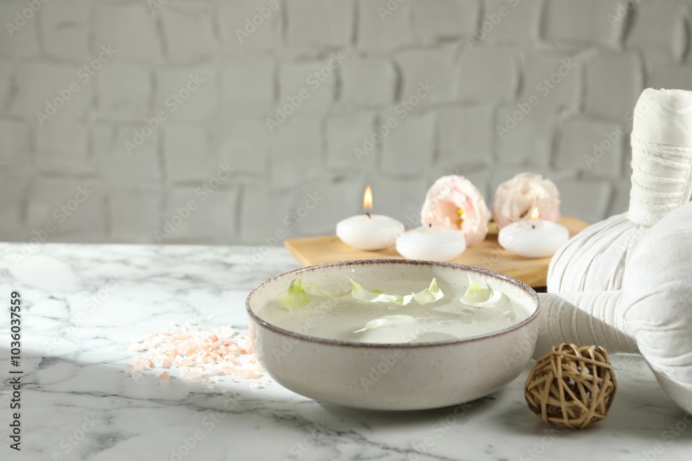 Sticker Spa composition with bowl of water and burning candles on white marble table, space for text