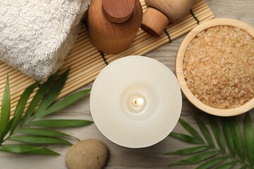 Spa composition with burning candle on wooden table, flat lay