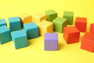 Many wooden colorful cubes on yellow background, closeup