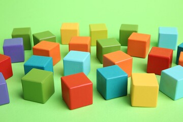 Many wooden colorful cubes on green background, closeup