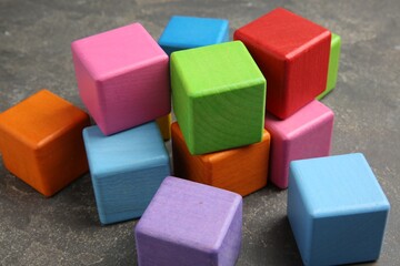 Many wooden colorful cubes on gray textured background, closeup