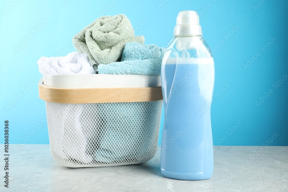 Poster Laundry detergent in bottle and towels on grey marble table against light blue background