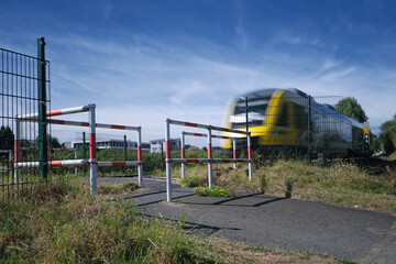 Bahnübergang für Fußgänger und Umlaufgitter und herannahender Zug - Stockfoto