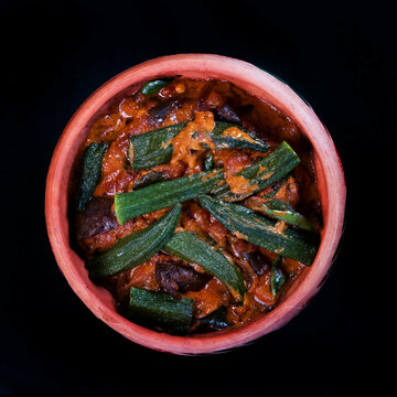 Bhindi masala or Okra masala or ladies finger curry in a clay  bowl isolated on black background