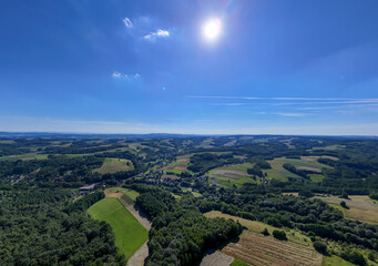 Fototapeta premium A stunning aerial view of lush green fields and rolling hills under a bright blue sky with soft clouds. A vibrant landscape showcasing nature's beauty.