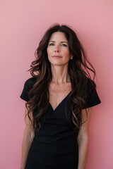 Naklejka premium Elegant Woman with Long Brown Hair Against Pink Background for Fashion and Portrait Photography