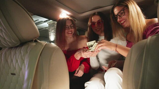 POV Three Joyful girlfriends Split the Fare and Pay the Taxi Driver with Dollar Bills, Laughing and Enjoying Their Ride Together
