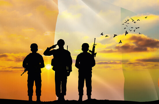 Silhouettes of soldiers with a background of the Ivory Coast flag and a sunset or sunrise. Concept of national holidays. Commemoration Day.