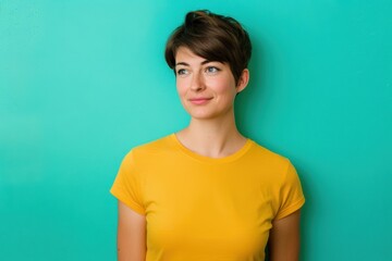 Fototapeta premium Confident Woman in Yellow T-Shirt Against Vibrant Teal Background for Modern Design
