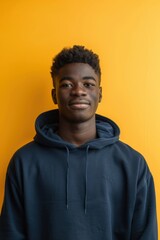 Fototapeta premium Young Man in Navy Hoodie Against Vibrant Yellow Background for Modern Portrait Photography