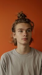 Fototapeta premium Relaxed Young Man with Blonde Hair Against Vibrant Orange Background for Portrait Design