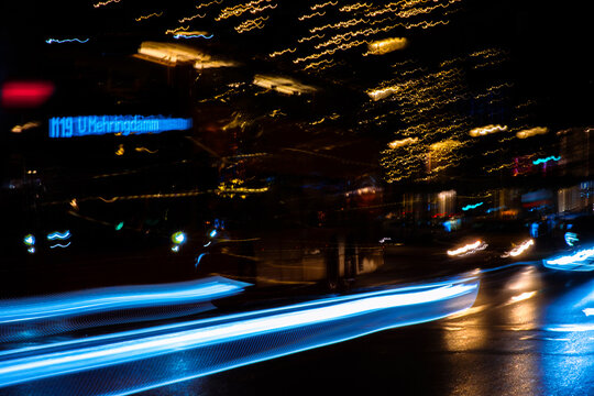 Long-exposure night shot of Berlin at night, glowing holiday lights with city traffic. Abstract cityscape at night, blue light trails and blurred street motion. Bus line M19 Mehringdamm
