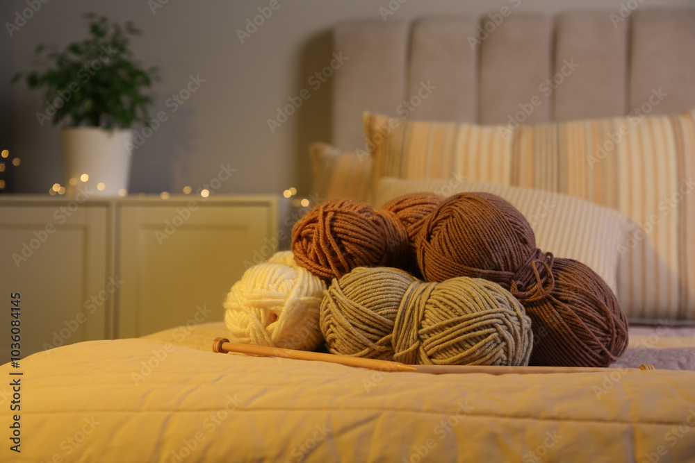 Wall mural Skeins of soft yarn and knitting needles on bed indoors