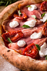 Close-Up of Gourmet Pizza with Prosciutto and Sun-Dried Tomatoes