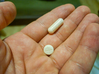 A close-up of a hand holding two white pills, highlighting the importance of medication and health....