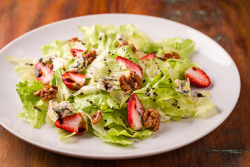Fresh Green Salad with Strawberries and Walnuts on White Plate