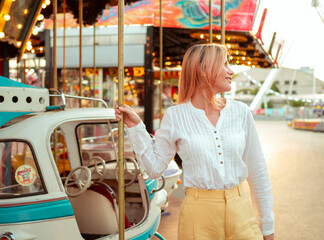 portrait of smiling young woman on the carousel at the amusement park. Leisure and entertainment at...