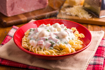 Delicious Creamy Pasta With Ham and Vegetables in Red Bowl