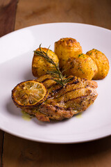 Grilled Chicken With Lemon And Herb Roasted Potatoes On White Plate