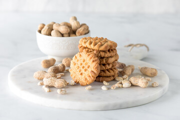 A stack of homemade peanut butter cookies surrounded by peanuts.
