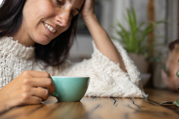 Close-up happy young woman smiling in a cafe holding a cup of matcha tea, art with heart shape milk, cappuccino coffee with foam and heart, espresso coffee, decoration with plants, vegan hot drink
