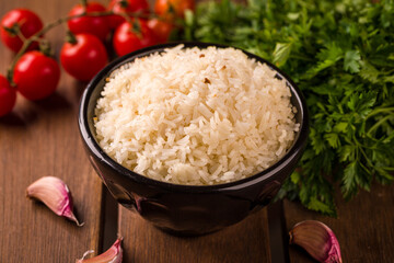 Delicious White Rice in Black Bowl with Fresh Vegetables