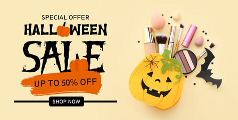 Bag in shape of pumpkin with makeup products and Halloween decor on beige background