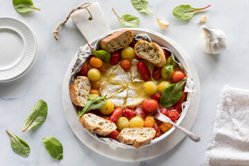 A roasted tomato and brie appetizer with baguette pieces for dipping.