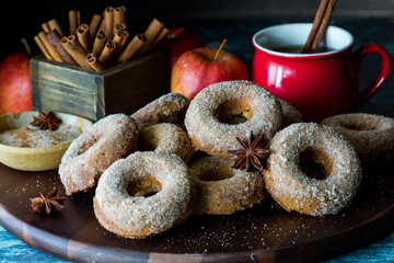 Chia orchard doughnuts on a wooden board with hot apple cider in behind.