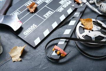 Clapperboard with film reel and different Halloween decor on grunge black background