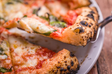 Close-Up of Traditional Neapolitan Margherita Pizza Slice Being Lifted