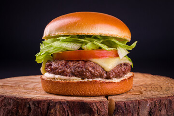 Delicious Cheeseburger with Fresh Lettuce and Tomato on Wooden Board