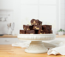 Homemade Chocolate Pecan Fudge on a White Pedestal  on Kitchen Counter