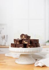 Homemade Chocolate Pecan Fudge on a White Pedestal  on Kitchen Counter