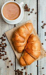 Breakfast with cup of coffee and fresh croissant. Flat lay. Top view. Homemade croissant with black coffee or americano