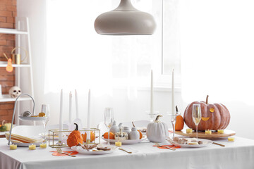 Beautiful table setting with pumpkins and burning candles for Halloween party at home