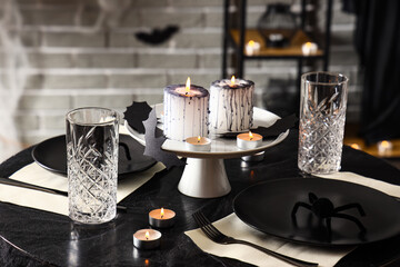 Festive table setting with burning candles and spiders for Halloween party
